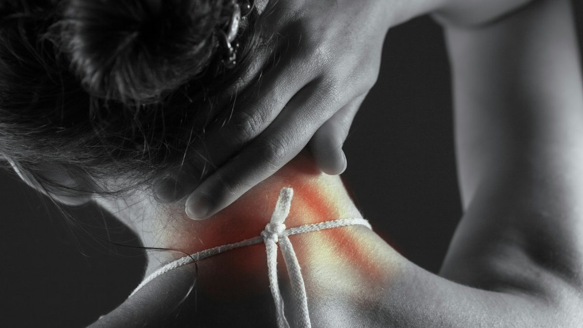 Mulher com mão sobre a região cervical em imagem que representa dor no pescoço