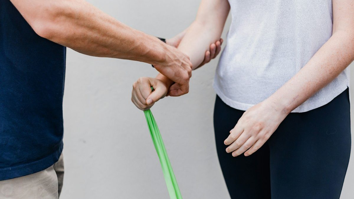 Duas pessoas em ambiente de exercícios, com orientação e uso de bastão como recurso de treinamento